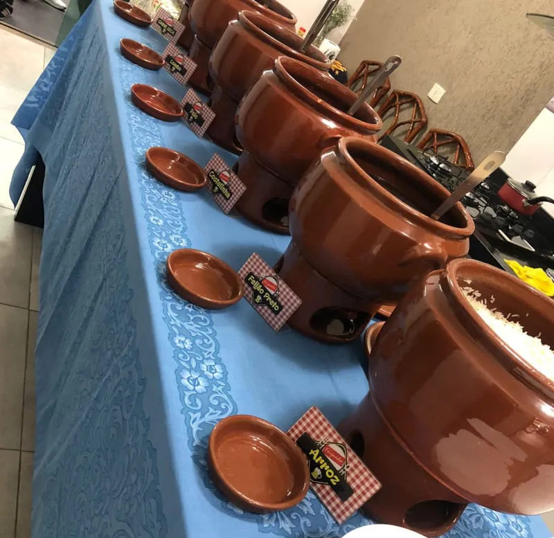 Fileira de cumbucas de feijoada montadas para evento em SP